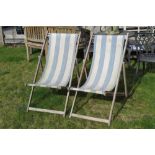A pair of wooden framed deck chairs.