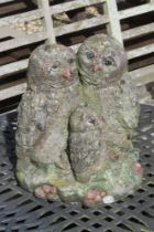 A pre-cast and painted garden statue of three owls standing 32cm high.