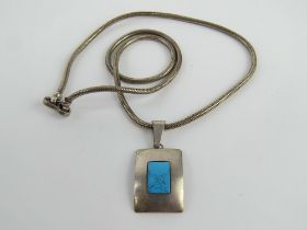 A geometric Scandinavian style turquoise pendant on substantial articulated snake link chain having