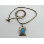 A geometric Scandinavian style turquoise pendant on substantial articulated snake link chain having