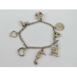 An HM silver charm bracelet having part padlock clasp and seven charms upon,