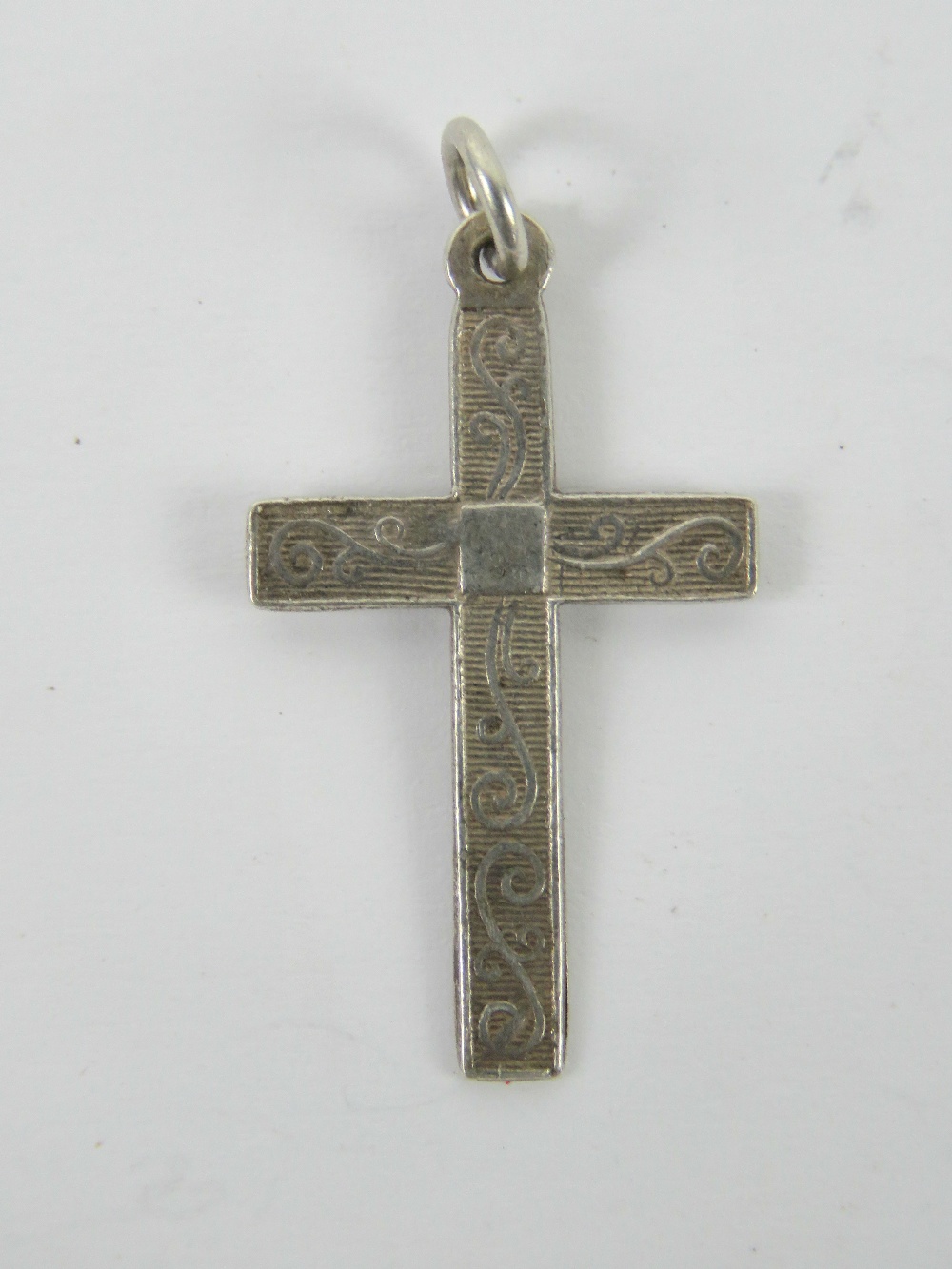 A silver crucifix pendant having scrolling engraving to front, stamped silver, 3.