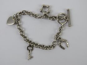 A HM silver charm bracelet having T-bar clasp and four charms upon being daisy, heart,