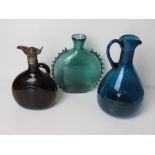 Three assorted coloured glass claret jugs, one having metal lid and cover,