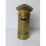 A brass money box in the form of a postbox, having VR cypher to front and standing 17cm high.