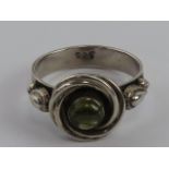 A silver and green stone ring having central cabachon with wreath design, stamped 925, size R.