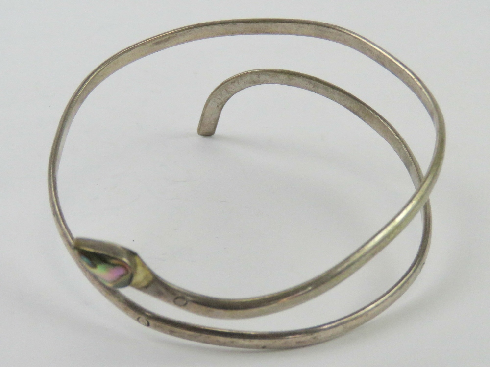A white metal upper arm bangle in the form of a coiled snake having Abalone shell head.