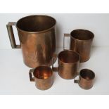 A set of five graduated copper measuring cups being gallon, quart, pint, half pint and gill.