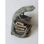 A Jill Moger sculpture of a lizard on a stack of books, standing 26.5cm high.