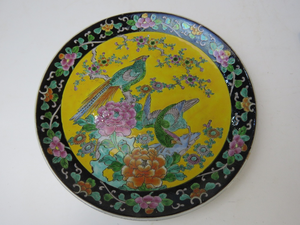 A Japanese ceramic charger in yellow ground having black ground border with floral decoration