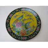 A Japanese ceramic charger in yellow ground having black ground border with floral decoration