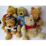 Five assorted Disney Winnie the Pooh cuddly toys.