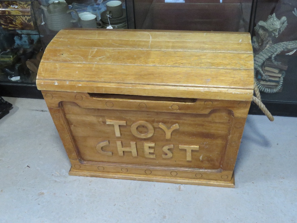 A wooden toy chest having rope end handles and domed lid, hinge a/f, approx 73cm wide.