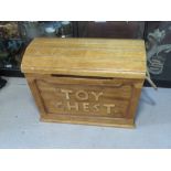 A wooden toy chest having rope end handles and domed lid, hinge a/f, approx 73cm wide.