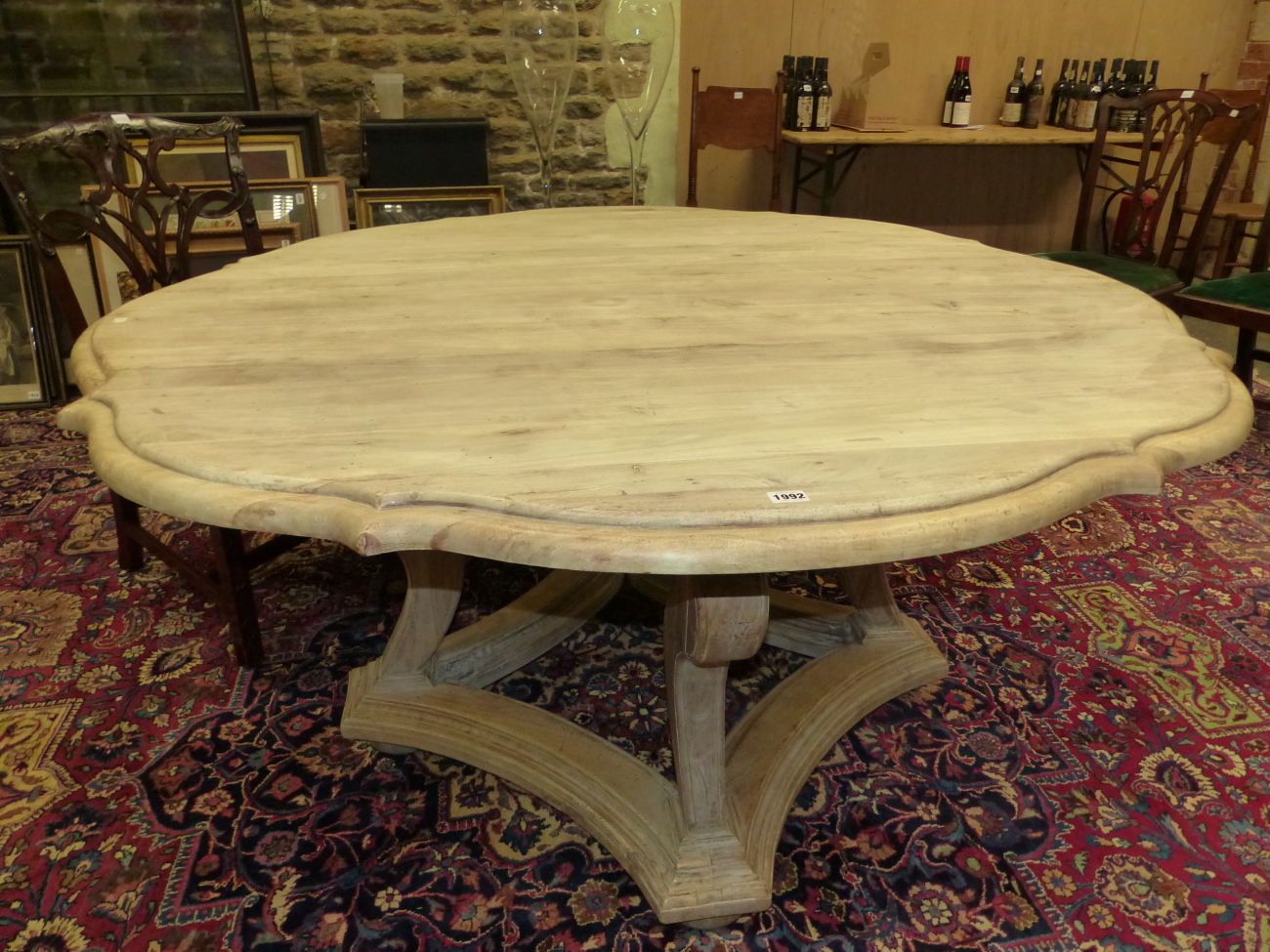 A BLEACHED OKA, "TUDOR ROSE" TABLE, THE SHAPED CIRCULAR TOP ON FOUR BRACKET LEGS JOINED BY A STRET