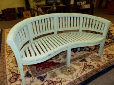 A GREEN PAINTED GARDEN BENCH, THE CURVED TOP RAIL ABOVE A SLATTED BACK AND SEAT ON SIX SQUARE SECTI