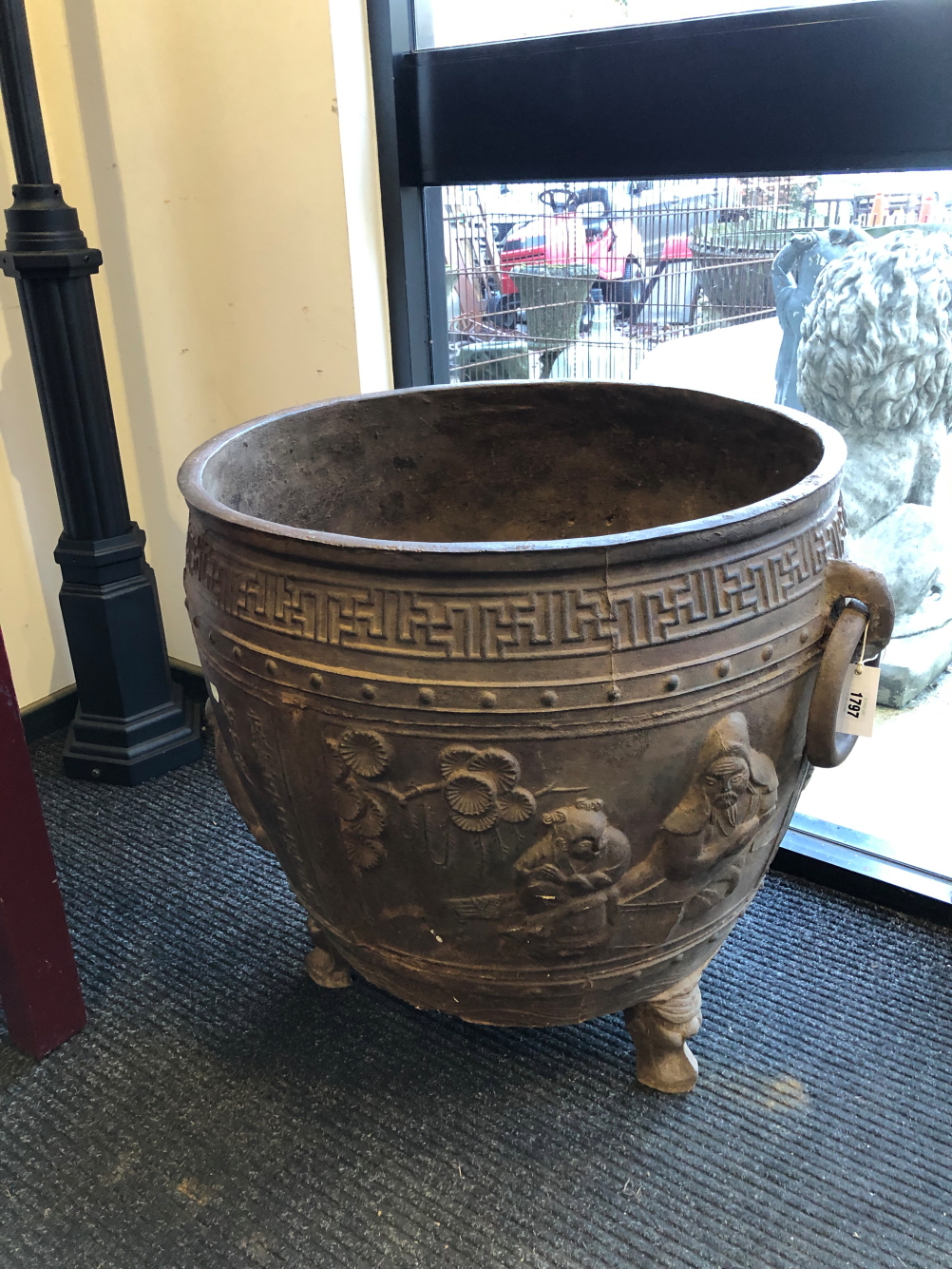A CHINESE CAST IRON RING HANDLED CAULDRON, THE ROUNDED SIDES CAST WITH FIGURES AND INSCRIPTIONS