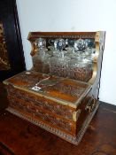 A VICTORIAN OAK THREE BOTTLE TANTALUS CARVED WITH GUILLOCHE BANDS, THE LID OF THE THREE COMPARTMENT