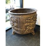 A CHINESE CAST IRON CAULDRON, THE ROUNDED SIDES CAST WITH FOUR PANELS OF FLOWERS ABOVE THREE MASK