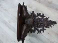 A 19th C. OAK WALL BRACKET, THE SHELF SEATED ON THE BACK OF A SPREAD EAGLE PERCHED ABOVE TWO PAIRS