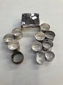 11 VARIOUS SILVER NAPKIN RINGS AND A SILVER CIGARETTE BOX.