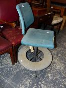 AN INDUSTRIAL DESK CHAIR WITH THE BLUE UPHOLSTERED SEAT ROTATING ABOVE A ALUMINIUM DISC FOOT REST