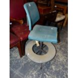 AN INDUSTRIAL DESK CHAIR WITH THE BLUE UPHOLSTERED SEAT ROTATING ABOVE A ALUMINIUM DISC FOOT REST