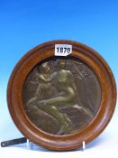 AN ART NOUVEAU BRONZE ROUNDEL CAST IN RELIEF WITH A NUDE LADY AND CHILD BELOW A TREE, INDISTINCTLY