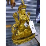 A TIBETAN GILT METAL FIGURE OF THE WHITE TARA SEATED ON A LOTUS THRONE, HER FACE AND HAIR WITH