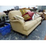 AN OATMEAL UPHOLSTERED TWO SEAT SETTEE ON MAHOGANY LEGS WITH BRASS CASTER FEET. W 157cms.