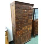 A VINTAGE OAK OFFICE FILE CABINET OF THREE BANKS OF NINE DRAWERS OVER THREE COMPARTMENTS WITH LIFT U