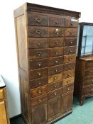 A VINTAGE OAK OFFICE FILE CABINET OF THREE BANKS OF NINE DRAWERS OVER THREE COMPARTMENTS WITH LIFT U