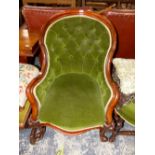 A VICTORIAN MAHOGANY SHOW FRAME ARMCHAIR BUTTON BACKED IN GREEN VELVET, A STOOL EN SUITE TOGETHER