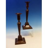 A PAIR OF LATE 18th C. BRONZE SQUARE BASE CANDLESTICKS WITH PUSHER CANDLE STUB EJECTORS. H 28cms.