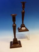 A PAIR OF LATE 18th C. BRONZE SQUARE BASE CANDLESTICKS WITH PUSHER CANDLE STUB EJECTORS. H 28cms.