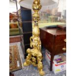 A CARVED GILT AND EBONISED STANDARD LAMP WORKED WITH MASKS AND FOLIAGE ABOVE THREE PAW FEET, THE