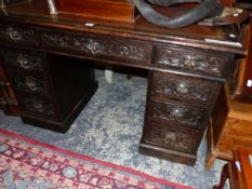A LATE VICTORIAN OAK PEDESTAL DESK, THE BROWN LEATHER INSET TOP OF A KNEEHOLE DRAWER FLANKED BY