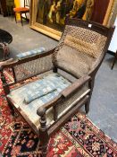 A 19th. C. MAHOGANY ARM CHAIR CANED AT THE BACK AND BELOW THE REEDED ARMS, THE RIBBED