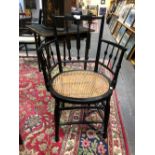 AN ARTS AND CRAFTS EBONISED ELBOW CHAIR IN MORRIS STYLE, THE THREE BARS TO THE BACK AND UNDER THE A