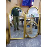 A PAIR OF SHAPED GILT FRAME DECORATIVE MIRRORS. 115 x 54cms. TOGETHER WITH AN OVAL BEVEL EDGE MIRROR