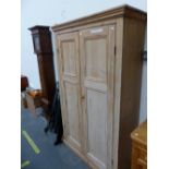 A VINTAGE PINE WARDROBE, THE TWO PANELLED DOORS ABOVE THE PLINTH FOOT. W 113 x D 41 x H 183cms.