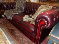 A RED LEATHER THREE SEAT CHESTERFIELD WITH BUTTONED BACK AND ARMS. W 194cms.