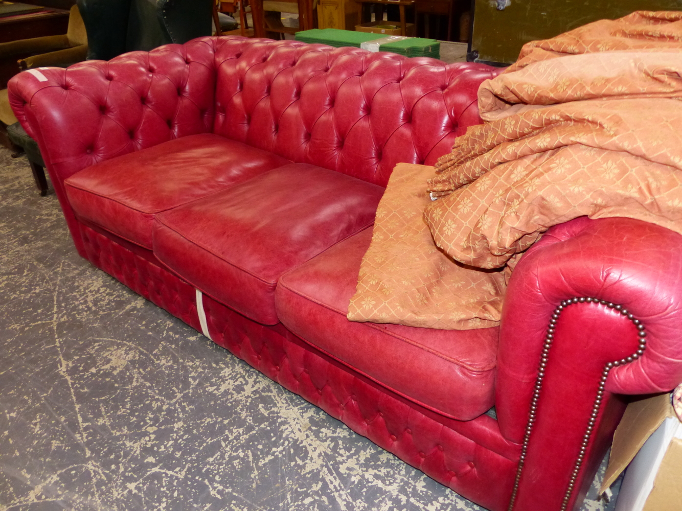 A BUTTONED RED LEATHER UPHOLSTERED THREE SEAT/SLEEP SOFA CHESTERFIELD. W 210cms