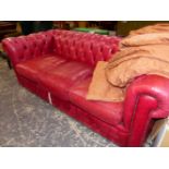A BUTTONED RED LEATHER UPHOLSTERED THREE SEAT/SLEEP SOFA CHESTERFIELD. W 210cms