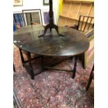 AN EARLY 18th C. OAK OVAL FLAP TOP TABLE, THE BALUSTER LEGS JOINED BY STRETCHERS ABOVE THE BUN FEET.