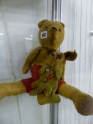 AN ANTIQUE JOINTED TEDDY BEAR AND A SMALL DOG PLUSH TOY.