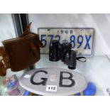 A PAIR OF COPPOCK BINOCULARS, A 1968 ONTARIO LICENCE PLATE AND A GB CAR BADGE.
