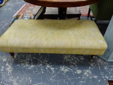 A MODERN MOTTLED BEIGE UPHOLSTERED STOOL ON MAHOGANY LEGS WITH BRASS CASTER FEET. W 125 x D 57 x H