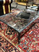 A GLASS TOPPED IRON COFFEE TABLE WITH SCROLLING FOLIAGE BELOW THE TOP AND ON LEGS OF THREE SQUARE