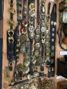 A COLLECTION OF HORSE BRASSES MAINLY PRESENTED ON LEATHER STRAPS